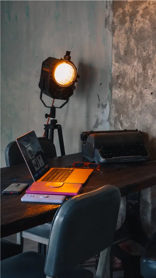 Queen of Compass Studio desk with a laptop, typewriter and studio light